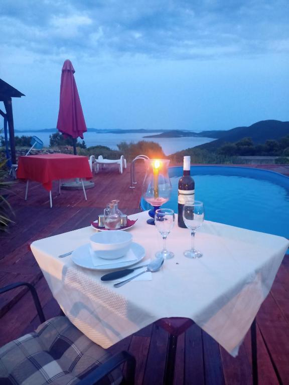 a table with a bottle of wine and two glasses at Apartments Ruža Dragove Dugi otok in Dragove