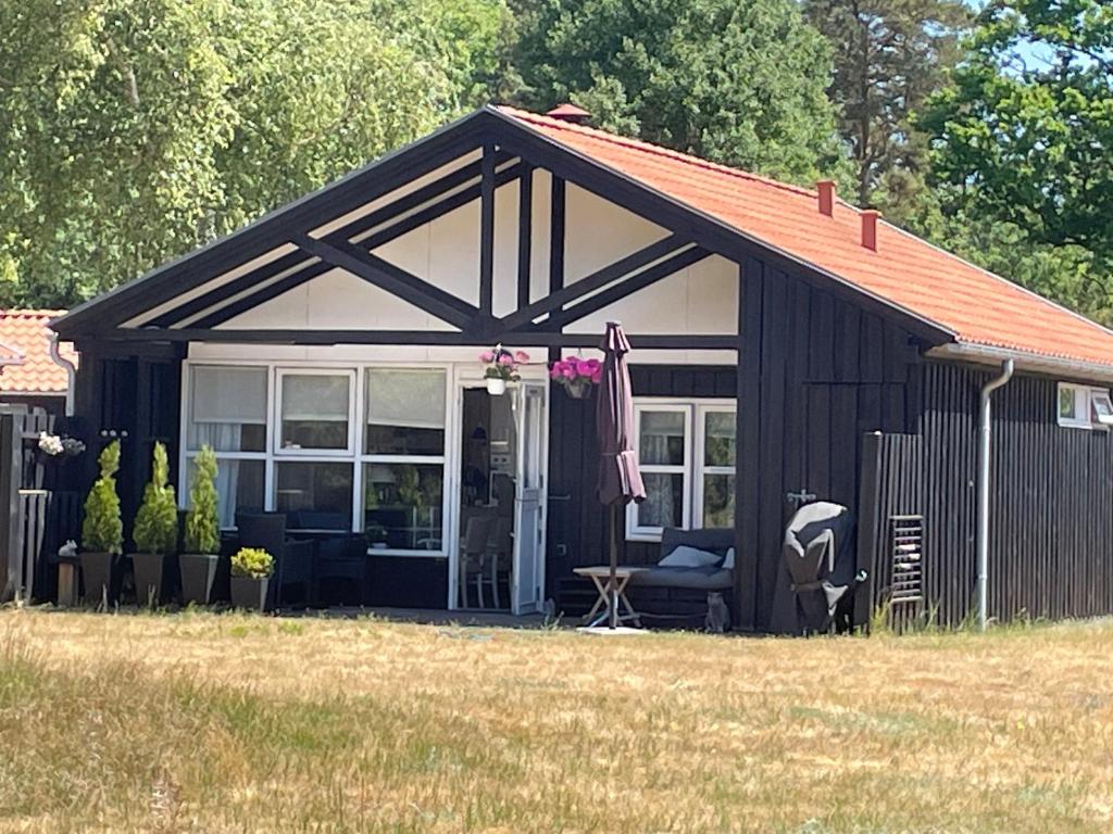 a black and white shed with a patio at Charmerende sommerhus - 200 m fra stranden in Marielyst