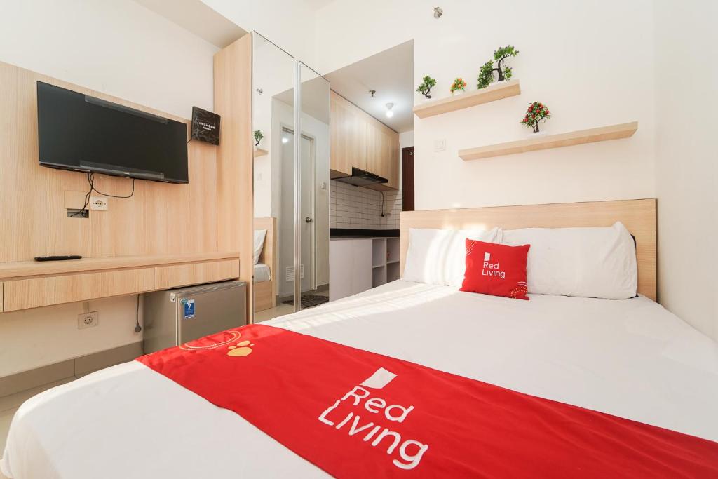 Un dormitorio con una cama con una manta roja. en RedLiving Apartemen Sayana - Premium Property, en Tambun-lobangbuaja