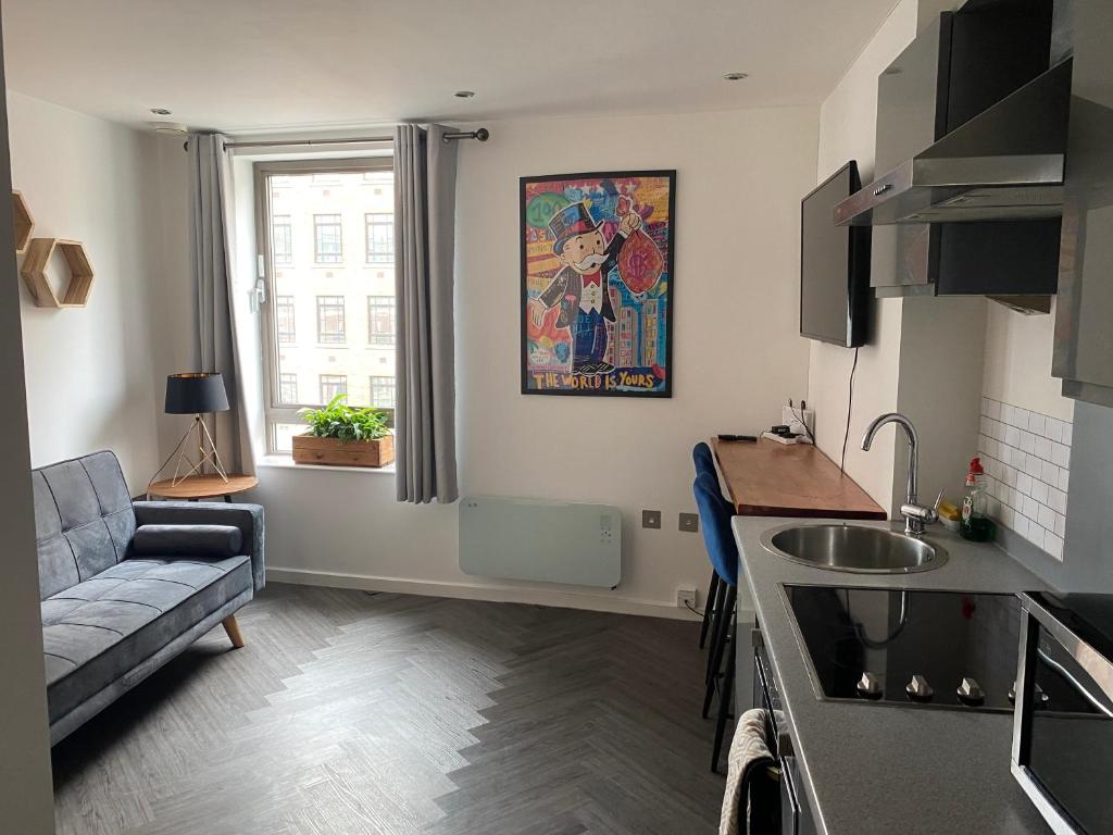 a kitchen and living room with a couch and a sink at Stunning apartment in the heart of Leeds in Leeds