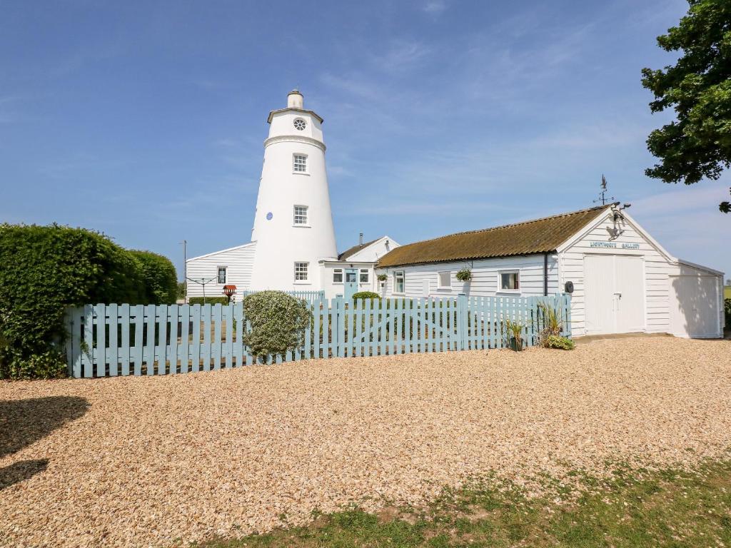 un phare avec une clôture blanche devant lui dans l'établissement The Sir Peter Scott Lighthouse, à Spalding