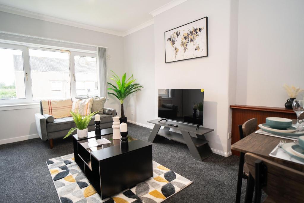 a living room with a couch and a tv at Linburn Apartment in Glasgow