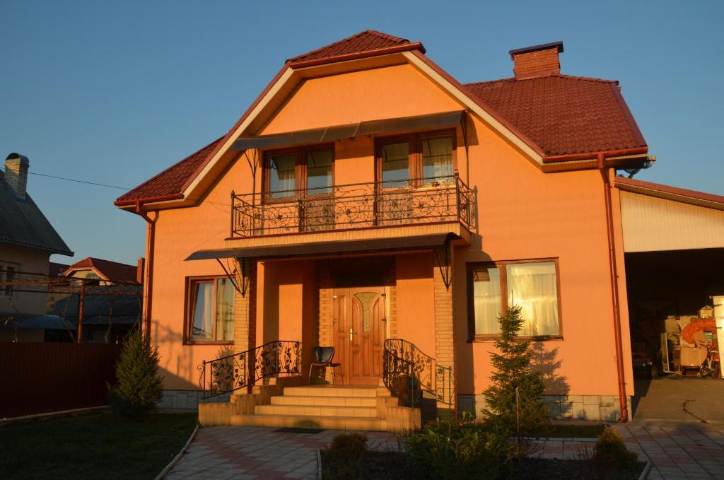 Dieses orangefarbene Haus verfügt über eine Veranda und einen Balkon. in der Unterkunft Semeyny Guest House in Uschhorod