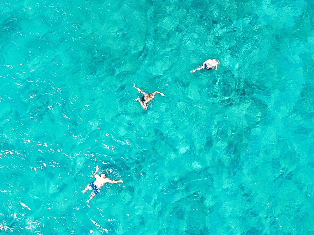 a group of people swimming in the blue water at MNS Marvelous Nirvana Seascape, Philosophy in Panayía
