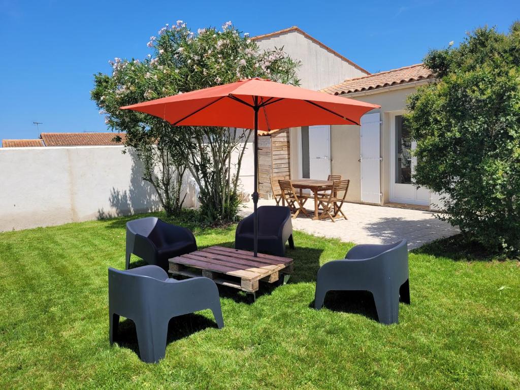 - une table de pique-nique avec un parasol et des chaises rouges dans l'établissement Maison sur ile d'Oléron, à Saint-Pierre-dʼOléron