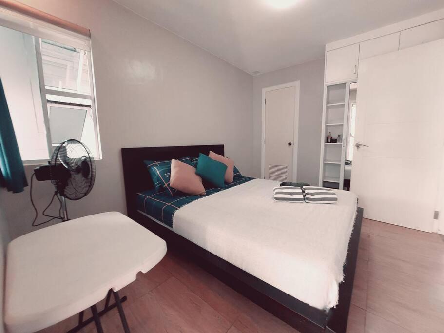 a bedroom with a large bed and a chair at The Two-Bedroom Balcony House Tagaytay in Tagaytay