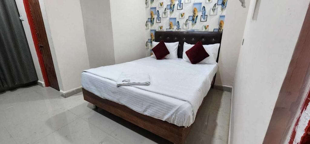 a bedroom with a bed with white sheets and red pillows at SPOT ON Hotel Ellora in Raipur