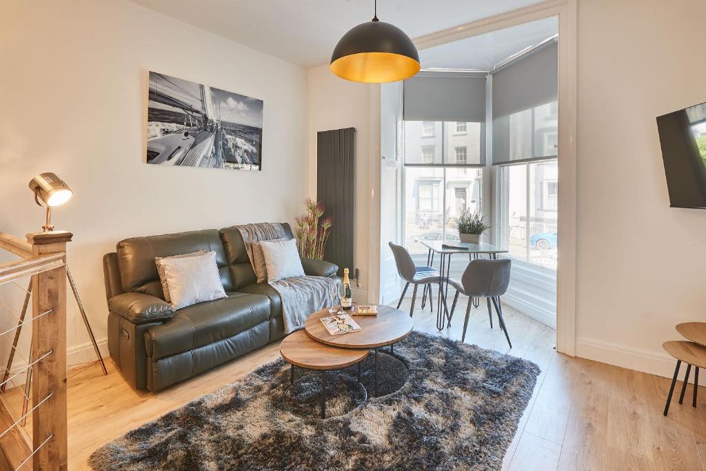 a living room with a leather couch and a table at Ocean Pearl Whitby in Whitby