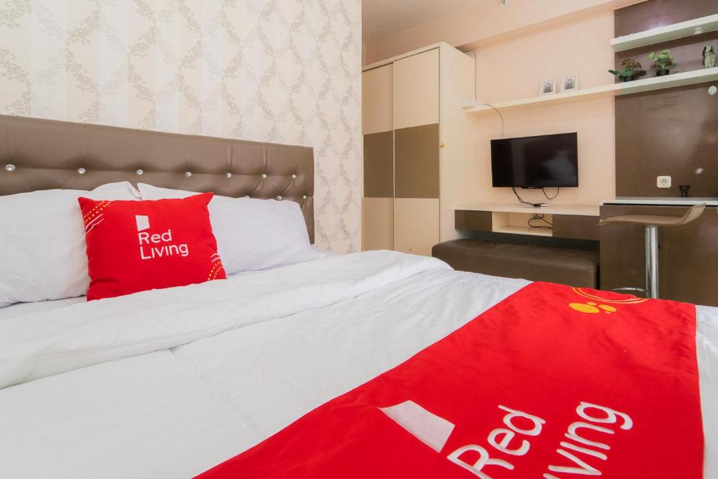 a hotel room with a bed with a red pillow at RedLiving Apartemen Bassura City - Premium Property in Jakarta