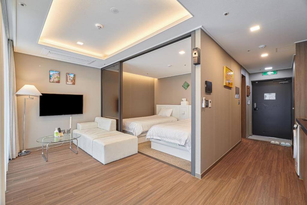 une chambre d'hôtel avec un lit et une télévision dans l'établissement Family Hotel & Arbol, à Busan