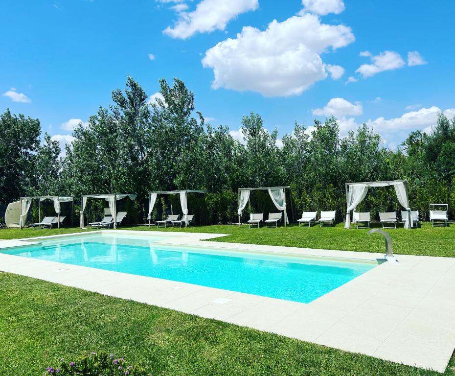 une piscine au milieu d'une pelouse avec des chaises dans l'établissement La Corte Della Regina, à Catane