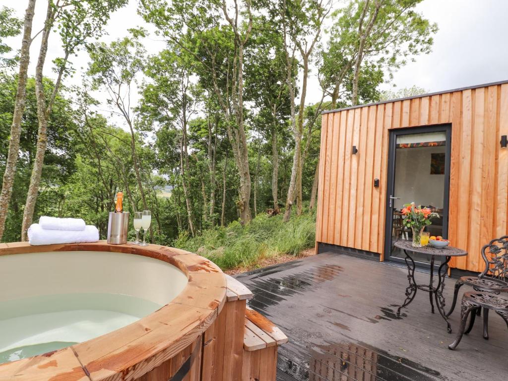 a wooden cabin with a bath tub on a deck at Bluebell Cabin in Penrith
