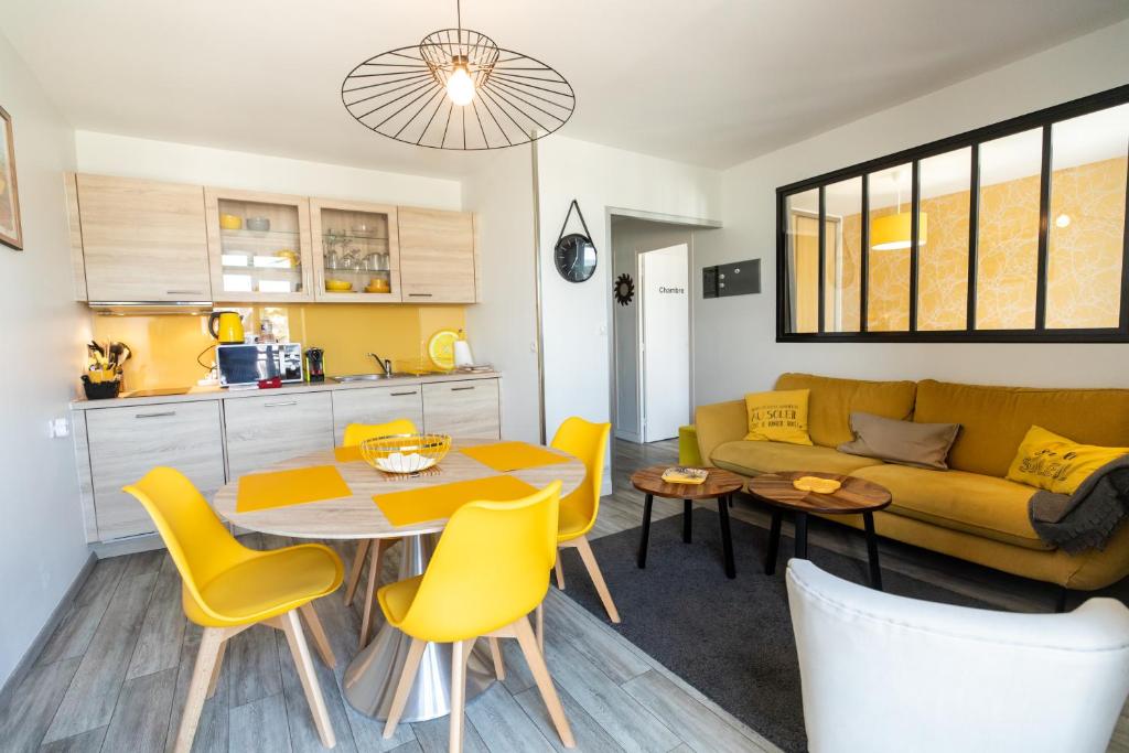 salon z kanapą, stołem i krzesłami w obiekcie Appartement - Le Soleil des Flots - Vue sur Mer w mieście Crozon
