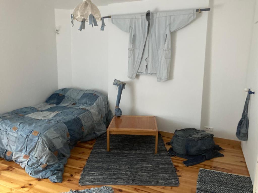 a bedroom with a bed and a table and clothes at CHAMBRE JEAN'S CHEZ L'HABITANT à LAMBALLE in Lamballe