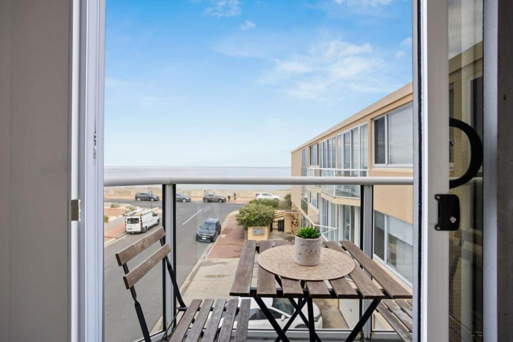 a balcony with a table and a view of a street at Sunset Sanctuary Glenelg Sth in Glenelg