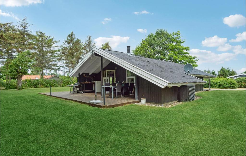 a small house with a deck in a yard at Amazing Home In Tranekr With Sauna in Skattebølle