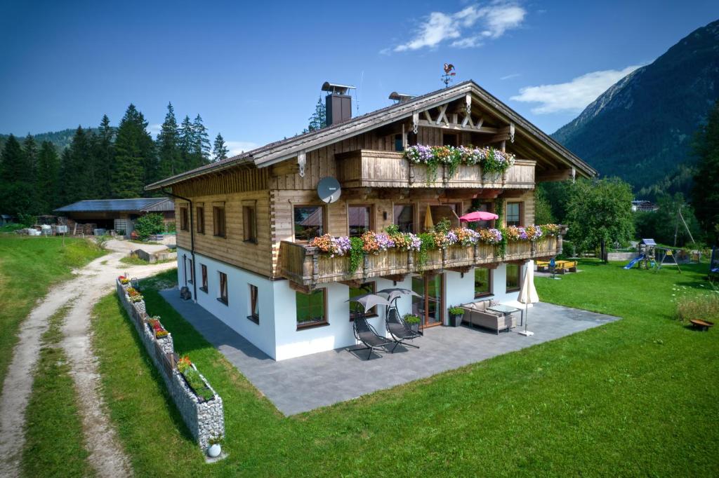 una casa con un balcón con flores. en Ferienwohnung Hinterwinkl en Achenkirch