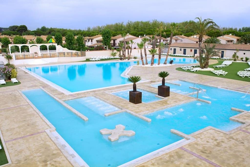 basen w ośrodku z niebieską wodą i palmami w obiekcie Maison à Portiragnes Plage - Résidence les Tamaris - Porte du Soleil - Prix piscine comprise w mieście Portiragnes