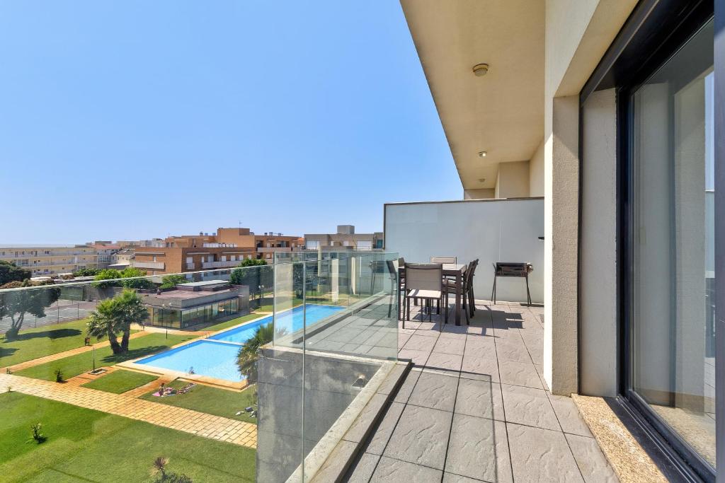 a balcony with a table and chairs and a pool at Sublime Mundo Apartamento in Apúlia