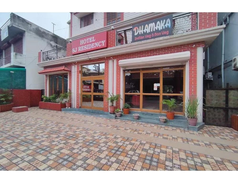 een winkel voor een bakstenen gebouw met potplanten bij Hotel SJ Residency, Dehradun in Dehradun