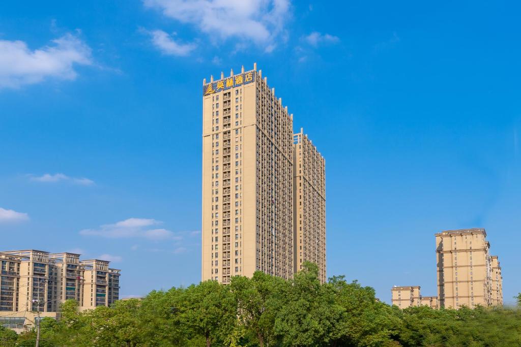 a tall building with trees in front at Morning Hotel, Wuxi Jiangnan University Sunac Cultural Tourism City in Wuxi