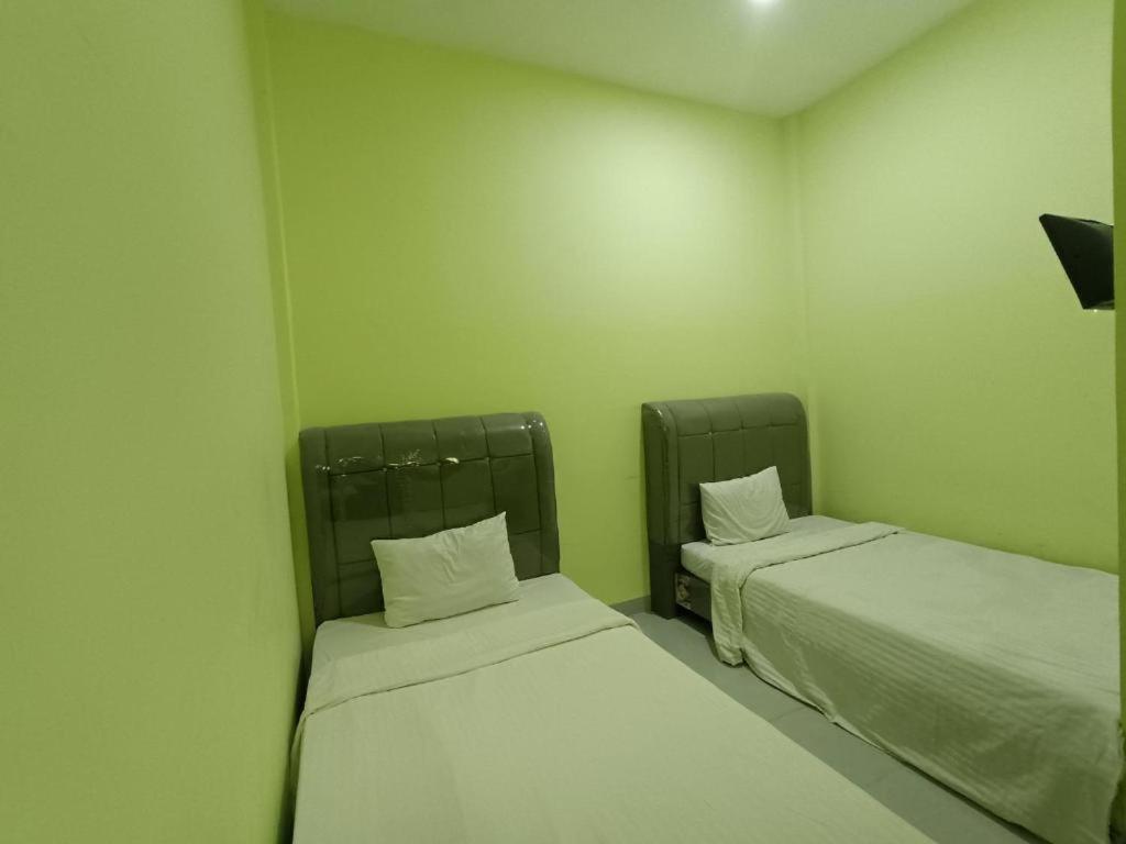 帕拉帕的住宿－Pudan Residence Parapat By Helocus，绿墙客房内的两张床