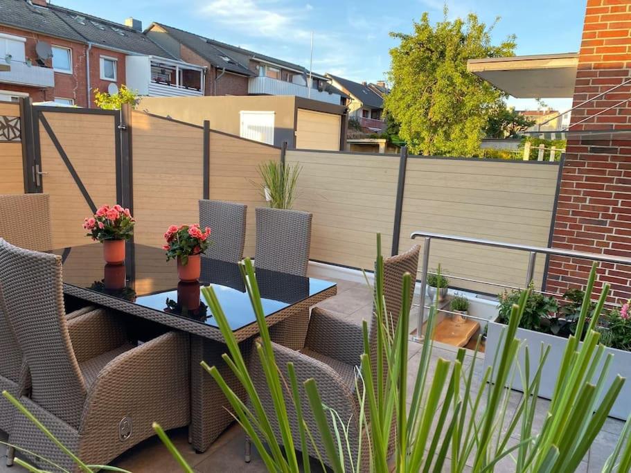 eine Terrasse mit einem Tisch, Stühlen und einem Zaun in der Unterkunft Ferienwohnung Hereinspaziert in Wilhelmshaven