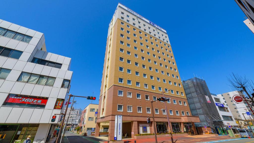 un edificio alto en la esquina de una calle de la ciudad en Toyoko Inn Hon-atsugi-eki Minami-guchi, en Atsugi