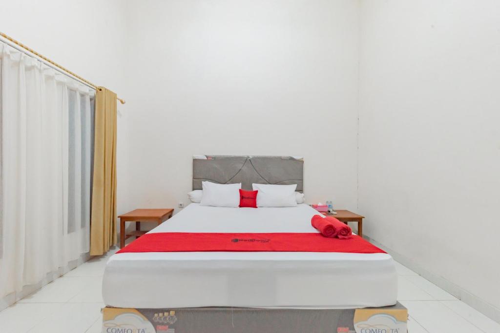 Un dormitorio con una cama con una manta roja. en RedDoorz near GOR Parenggean 
