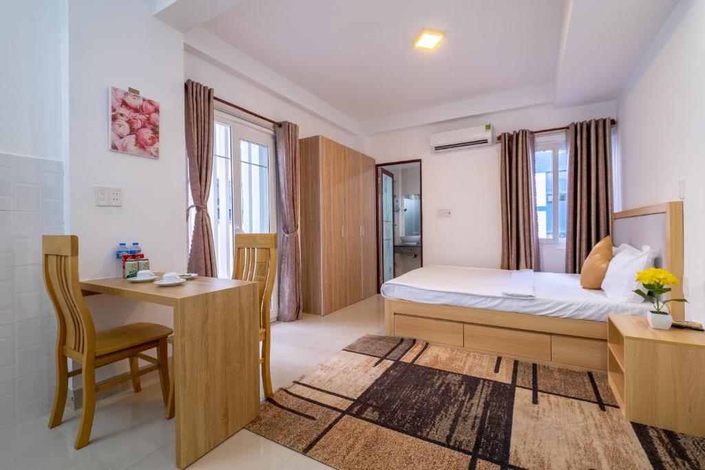 een slaapkamer met een bed, een bureau en een tafel bij Zuka Hotel & Apartment in Da Nang