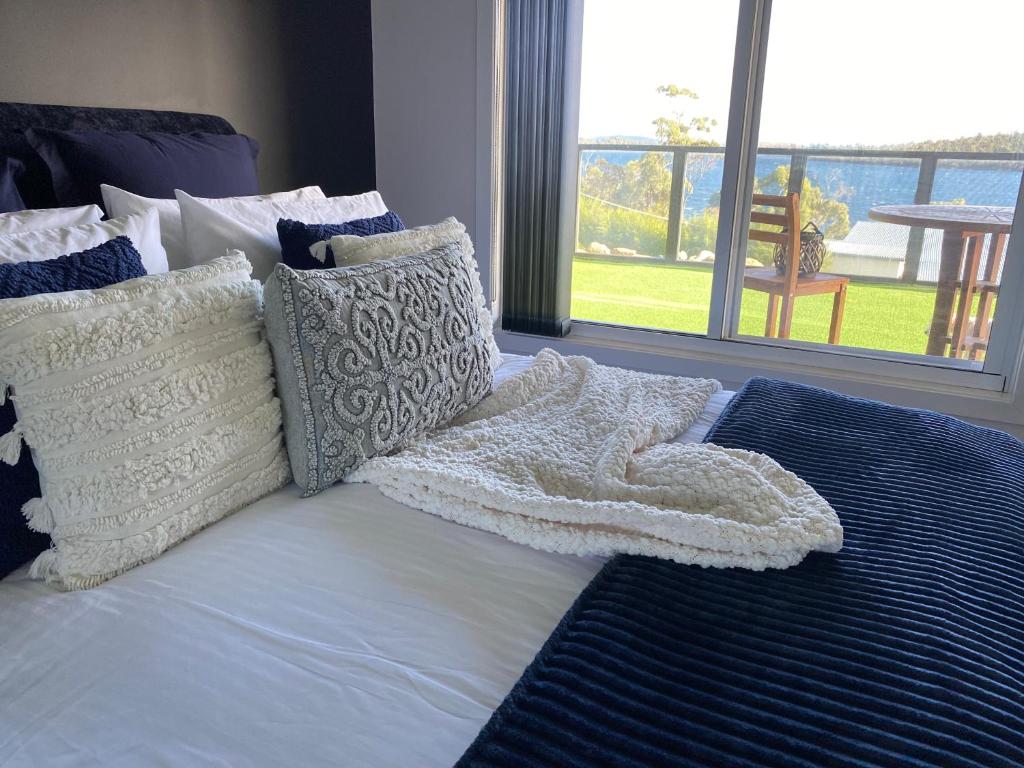 a bed with a white blanket and pillows on it at The Sounds in Murdunna