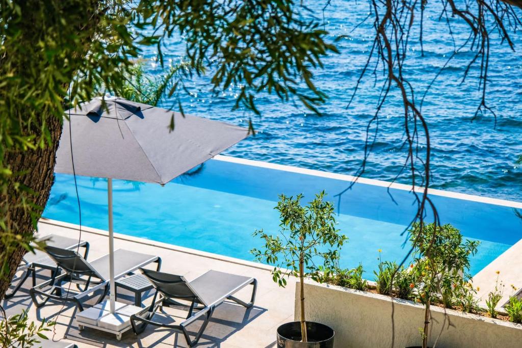 a patio with chairs and an umbrella next to the water at İsolina Bodrum in Bodrum City