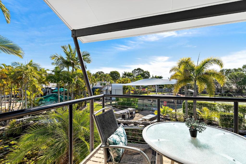 a balcony with a table and chairs and palm trees at Sun Drenched Unit in Noosaville in Noosaville