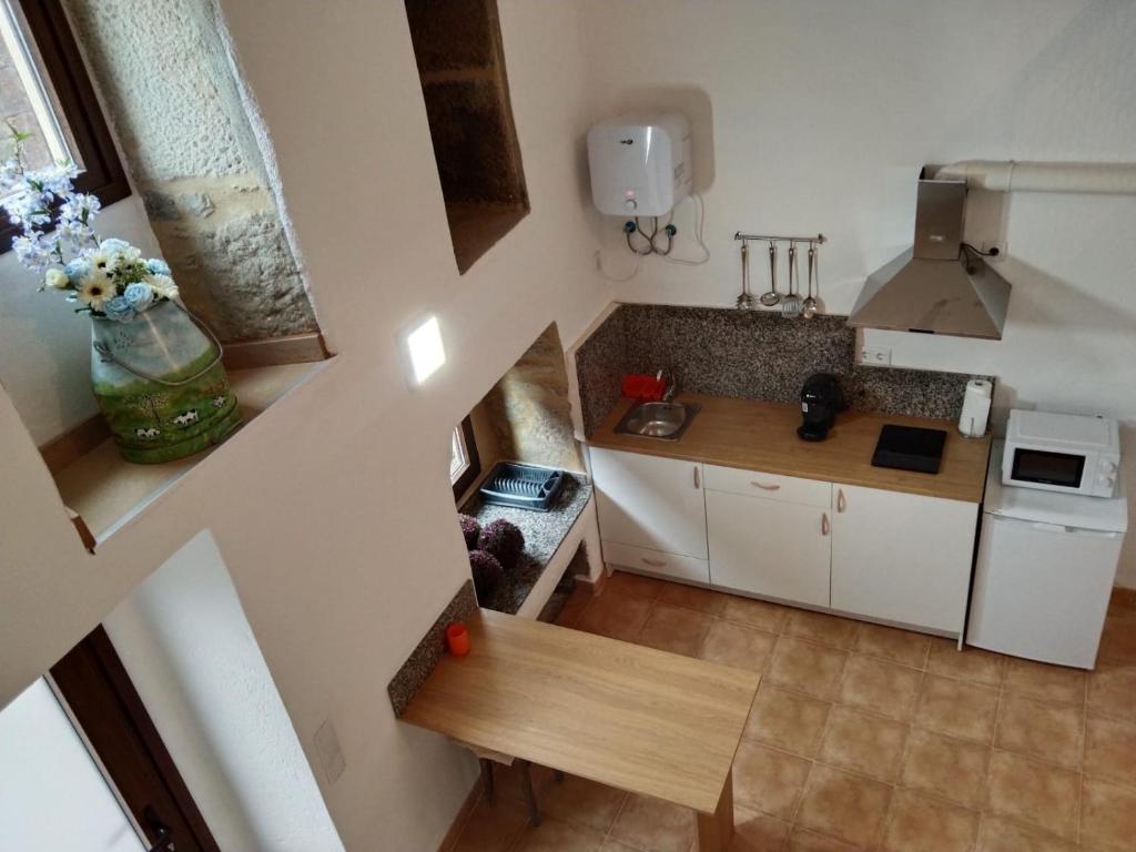 a small kitchen with white cabinets and a vase of flowers at A Casiña in Mazaricos