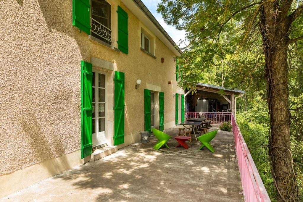 un edificio con persianas verdes y sillas verdes al aire libre en Une Poule Sur un mur, chambre d'hôte à Soulosse en Soulosse-sous-Saint-Élophe