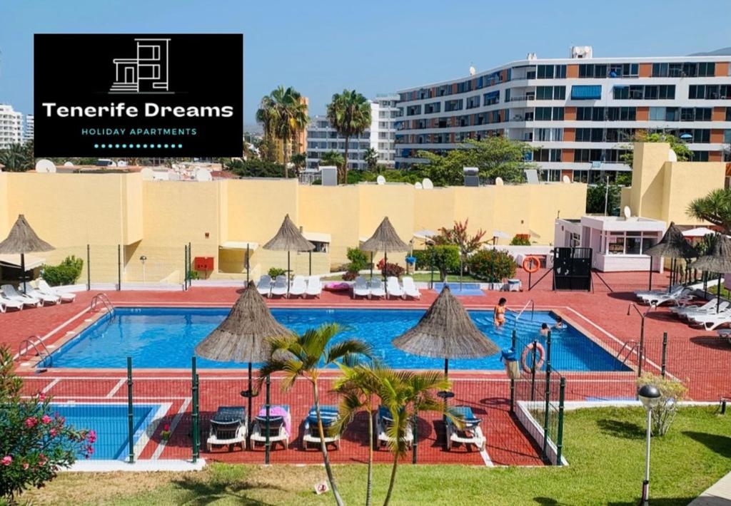 - une piscine avec des chaises et des parasols à côté d'un bâtiment dans l'établissement Dream Holiday Las Americas, à Playa de las Americas