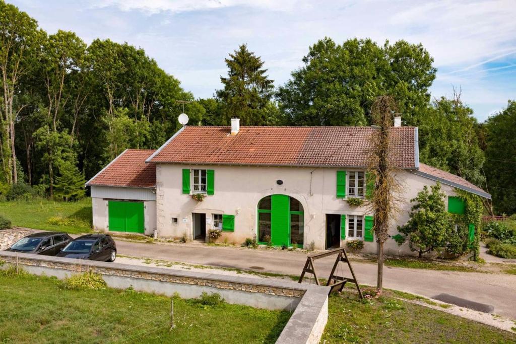 a house with green doors and a car parked in front at Jolie vache déguisée en fleurs, chambre d'hôte à Soulosse in Soulosse-sous-Saint-Élophe
