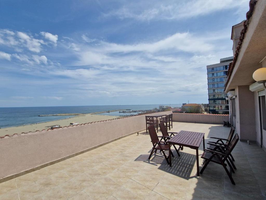 een balkon met stoelen en een tafel en het strand bij Leon Apartment in Constanţa