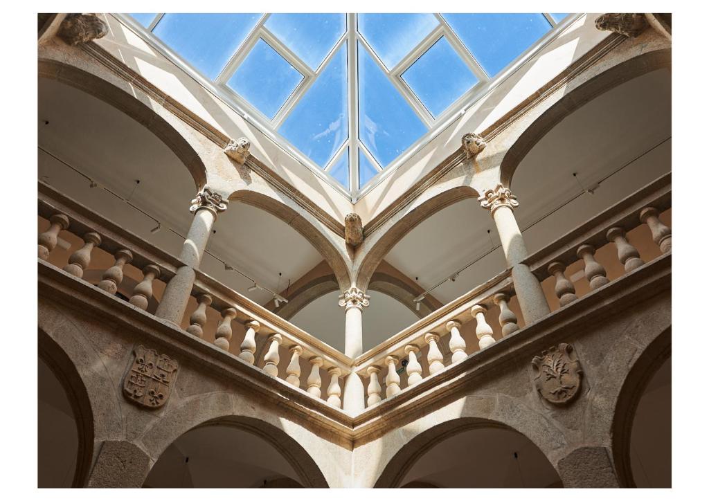a building with a glass ceiling with arches at Hotel Casa Palacio Pereros in Cáceres