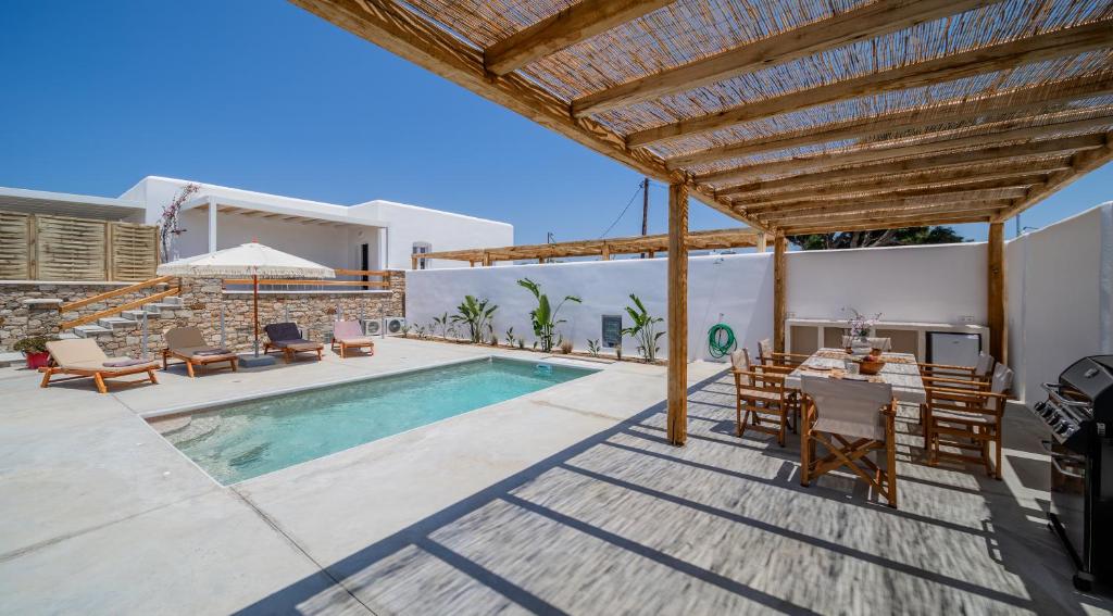 a villa with a swimming pool and a table and chairs at Petradia Villas in Naxos Chora
