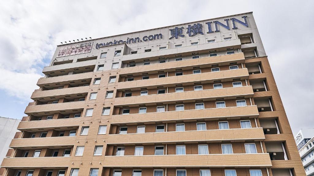 un edificio alto con un cartel encima en Toyoko Inn Osaka Itami Airport en Toyonaka