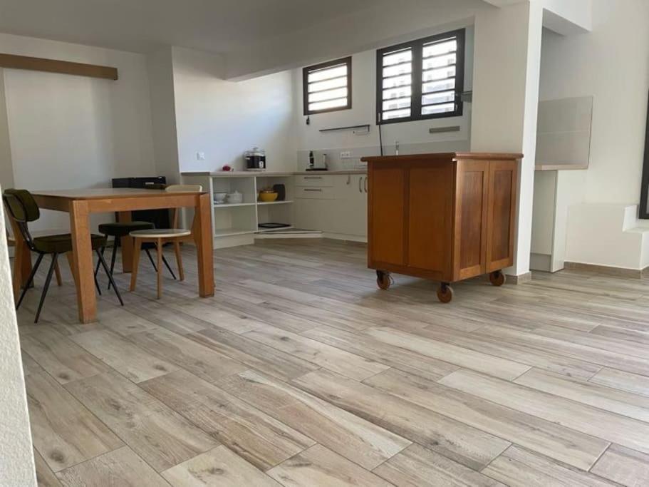 een kamer met een houten tafel en een keuken bij Chez Romuas in Le Tampon