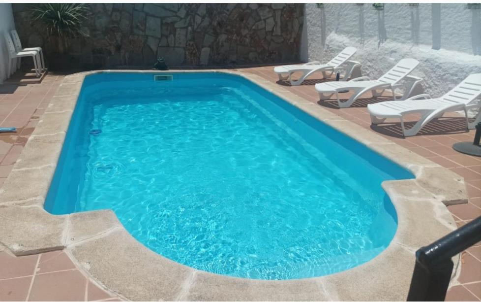 a swimming pool with chairs and a swimming pool at Casa Rural Tita Sacramento in Hornachos