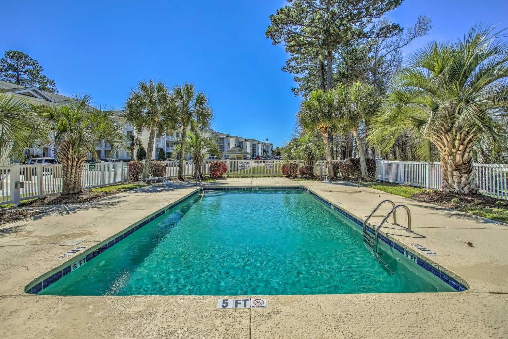 a swimming pool in a yard with palm trees at Myrtle Beach Condo Private Balcony and Resort Perks in Myrtle Beach