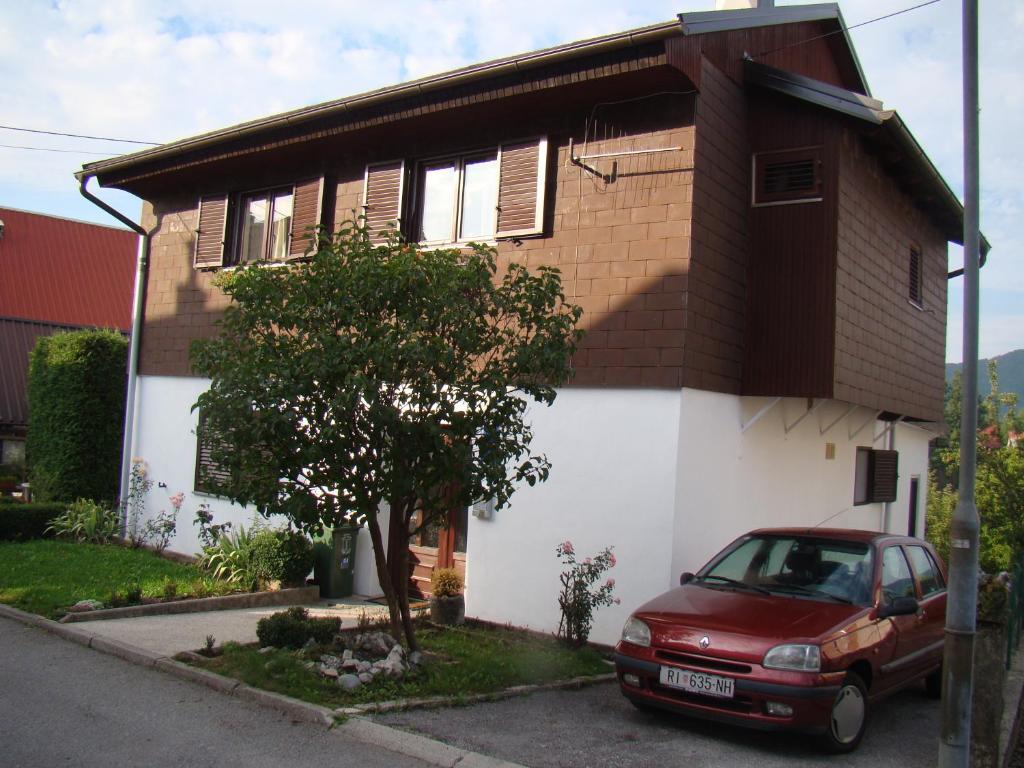 a red car parked in front of a house at Apartments Maroflin in Crni Lug