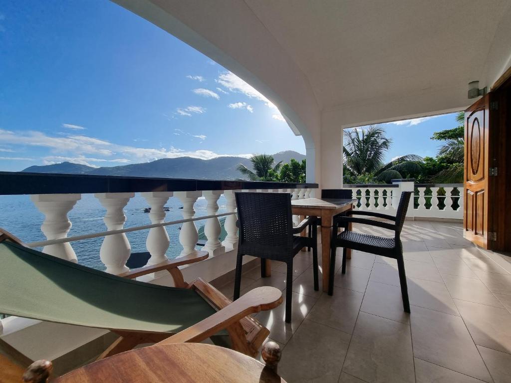 uma varanda com uma mesa, cadeiras e uma rede de descanso em The Drake Seaside Apartment em Bel Ombre