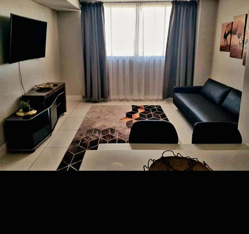 ein Wohnzimmer mit einem Sofa und einem TV in der Unterkunft Movic's Modern Airbnb in Windhoek