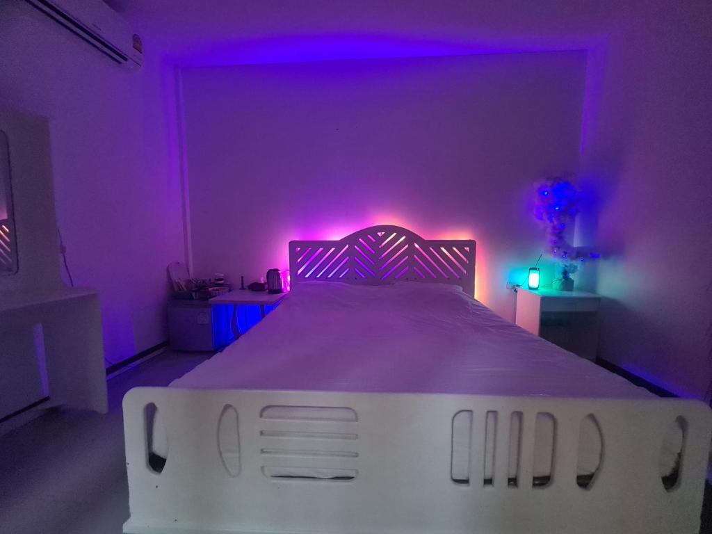 a bedroom with a white bed with purple lights at House by the sea in Haad Tian