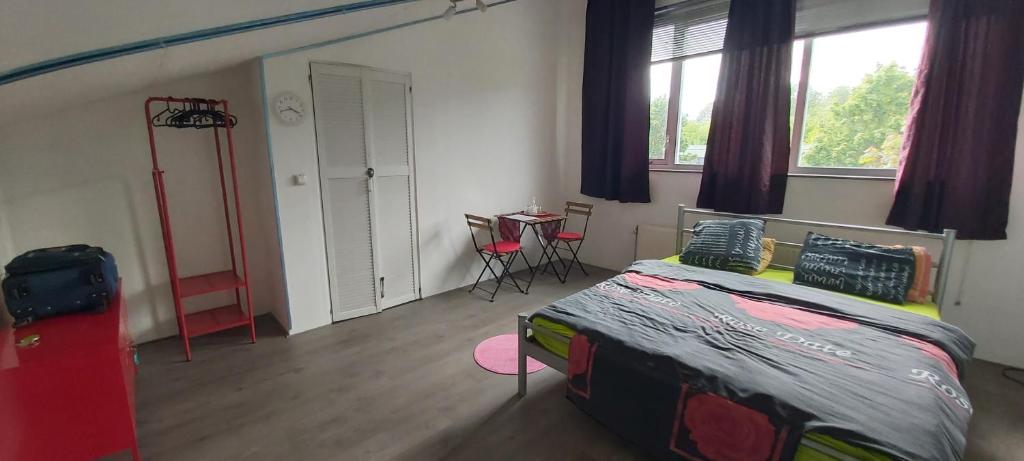 a bedroom with a bed and a table and windows at spacious room with free parking in Almere
