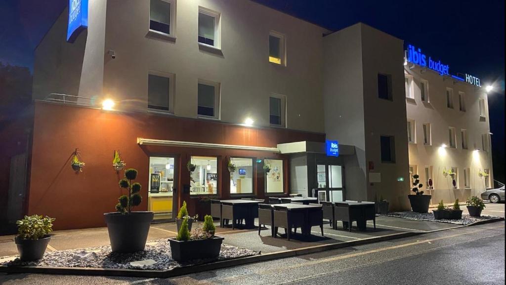 a hotel with tables and chairs in front of a building at ibis budget Noyon in Noyon